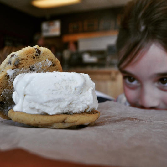 A girl enjoying a Cool Jacks cookie ice cream sandwich made with chocolate chip cookies and vanilla ice cream.