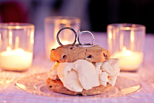 Ice cream cookie sandwich by Cool Jacks with wedding rings on top, lit by soft candlelight.