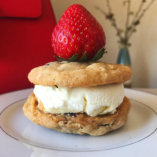 Cool Jacks cookie ice cream sandwich quartered and topped with a fresh strawberry, served on a white plate.