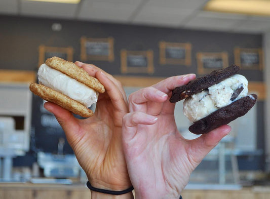 Two hands holding Cool Jacks ice cream sandwiches — one with snickerdoodle cookies and one with chocolate cookies.