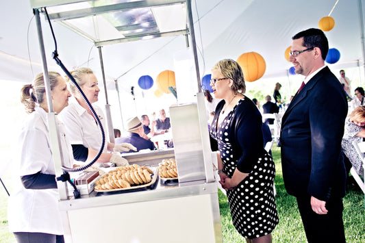The Cool Jacks Crew serves ice cream cookie sandwiches to guests at a wedding reception under a decorated tent.