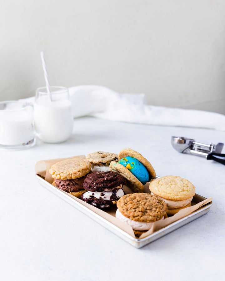A festive DIY Cool Jacks ice cream sandwich bar with toppings, sauces, and holiday decorations on a chilled serving tray.